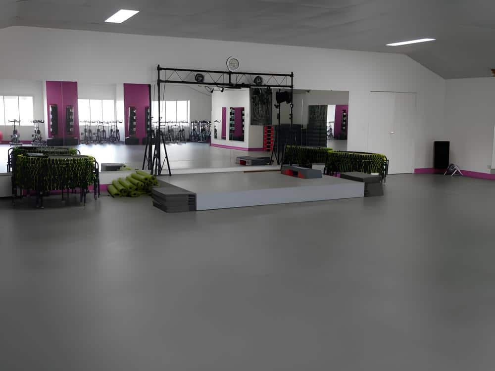 Appareils elliptiques Precor et salle de sport moderne Intérieur de salle de sport avec plusieurs elliptiques Precor modernes gris et noirs ; une horloge murale est visible sur un mur de briques rouges.