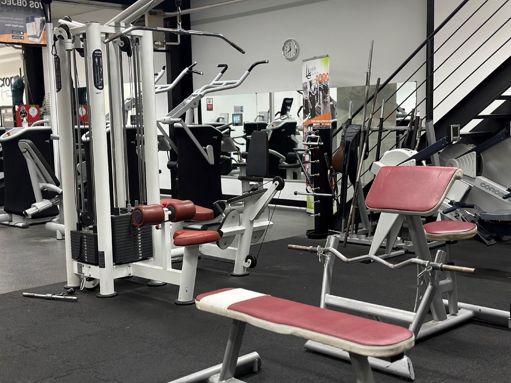 Appareils elliptiques Precor et salle de sport moderne Intérieur de salle de sport avec plusieurs elliptiques Precor modernes gris et noirs ; une horloge murale est visible sur un mur de briques rouges.